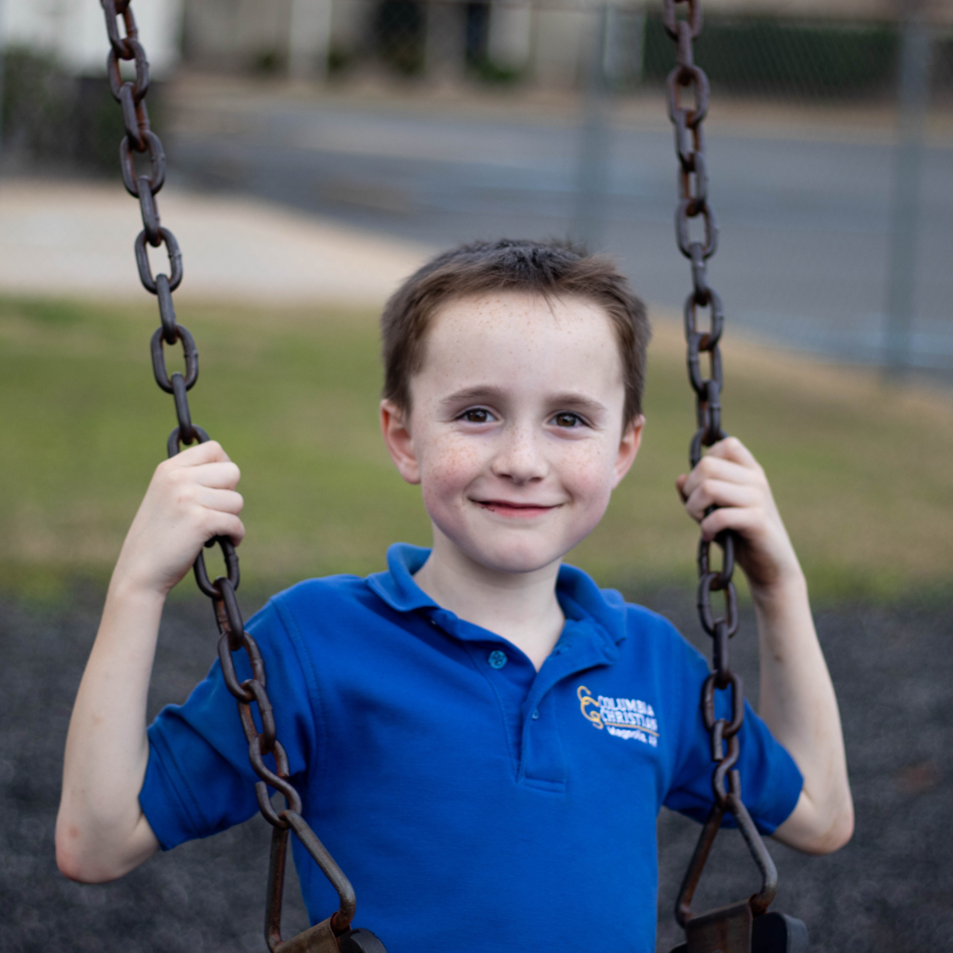 Columbia Christian academy student on the swing, smiling at the camera