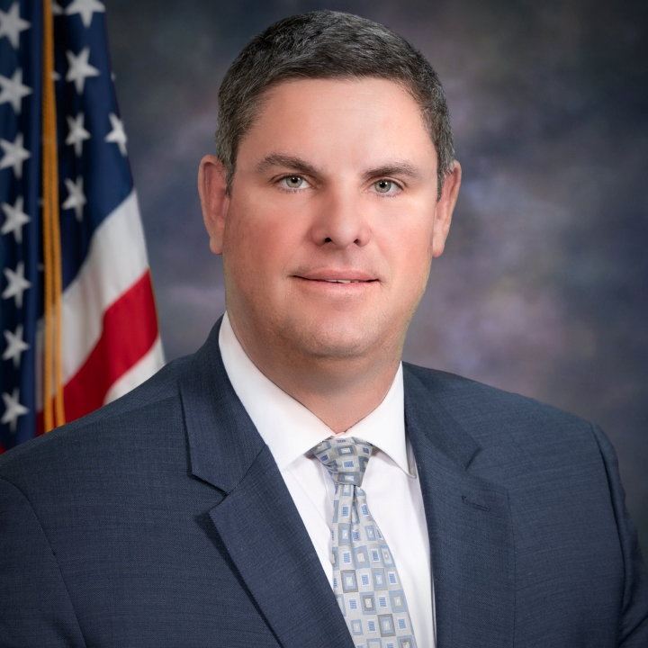 1. A man in a suit and tie stands confidently in front of an American flag, symbolizing patriotism and professionalism. 2. A man dressed in a suit and tie poses in front of an American flag, representing national pride and formal attire. 3. A man in formal attire stands before an American flag, conveying a sense of patriotism and professionalism.