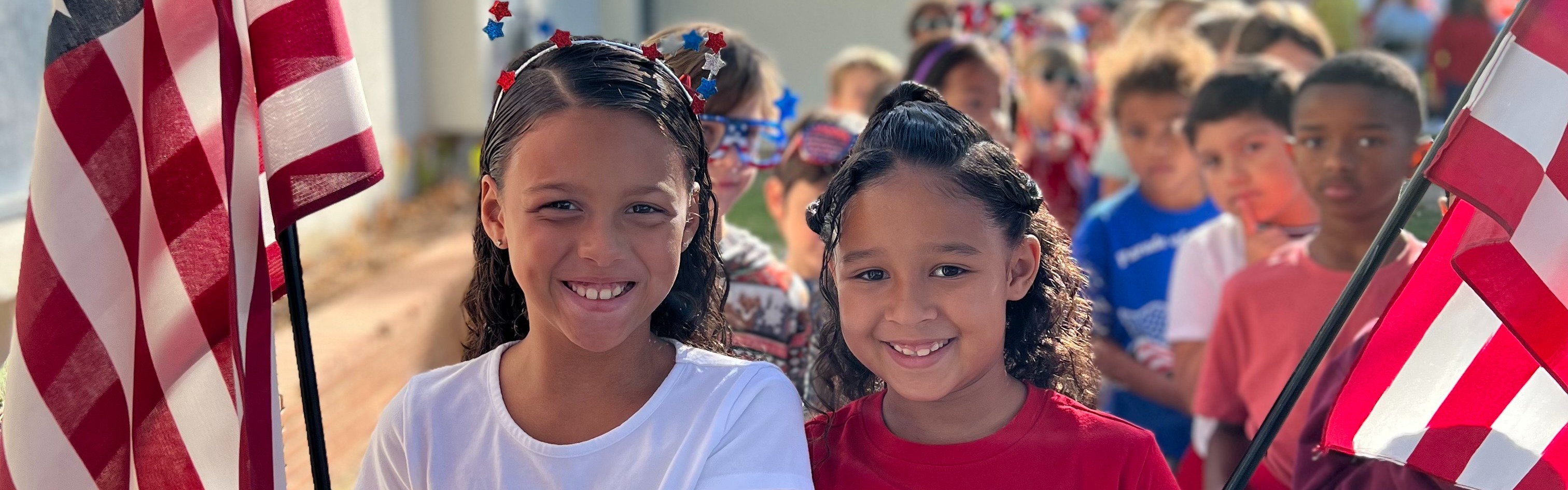 Students smiling waving  American flags