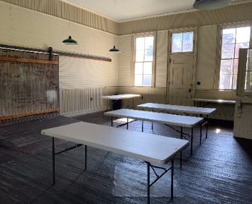 Interior of the old train depot with rows of white folding tables and rustic wooden walls.