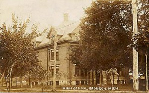 An old sepia-toned photo of a large, historic high school building surrounded by trees in Bronson, Michigan.