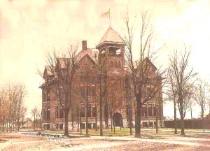 A large, old brick mansion with a tower, surrounded by leafless trees, under a cloudy sky.