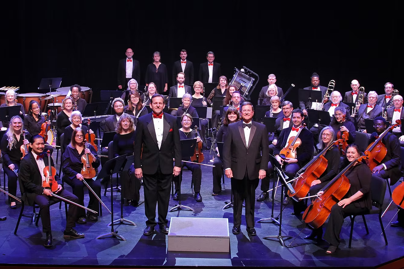 A picture of Lake Murray Symphony Orchestra members posing on a stage with their instruments