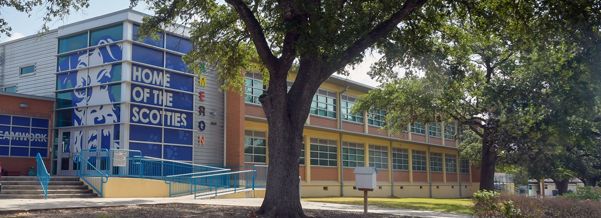 Colorful entrance to Bella Cameron Elementary school with trees in front and dog mascot painting on windows.