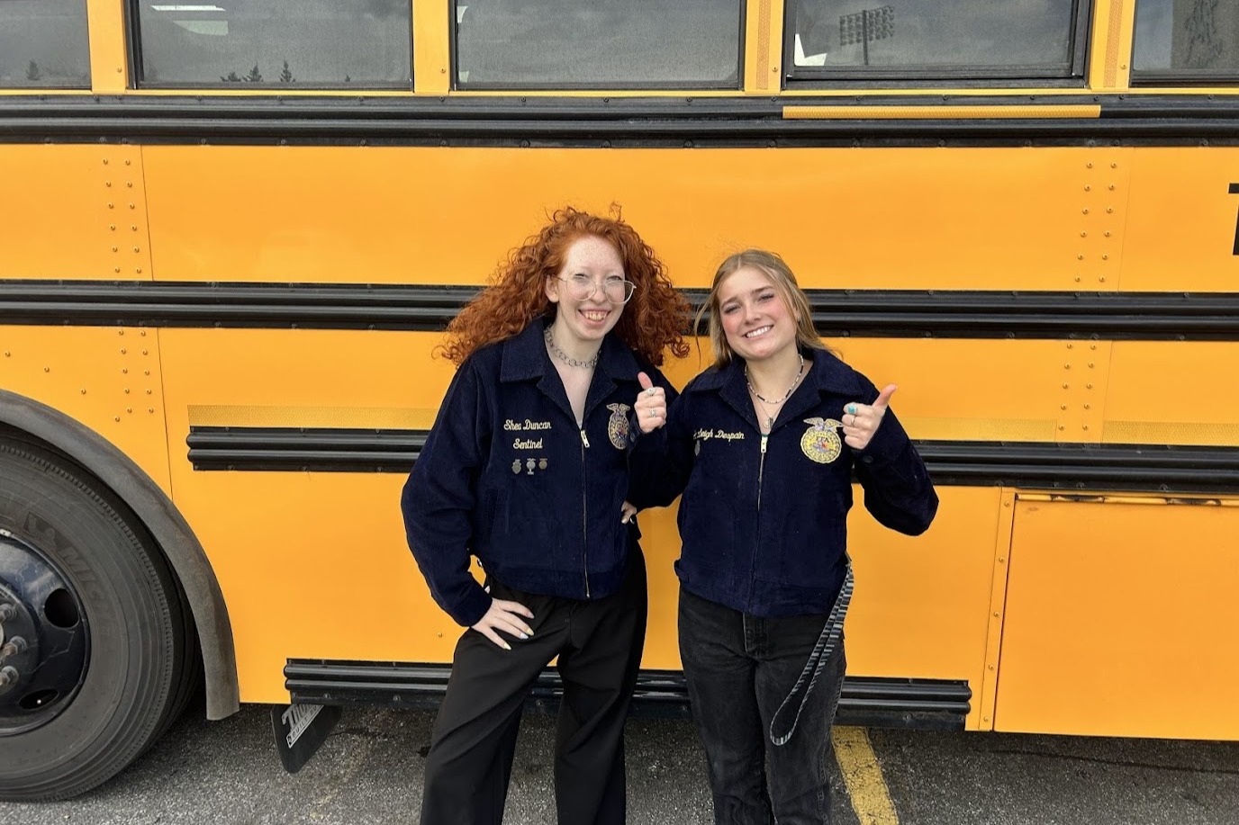 Two students next to a school bus