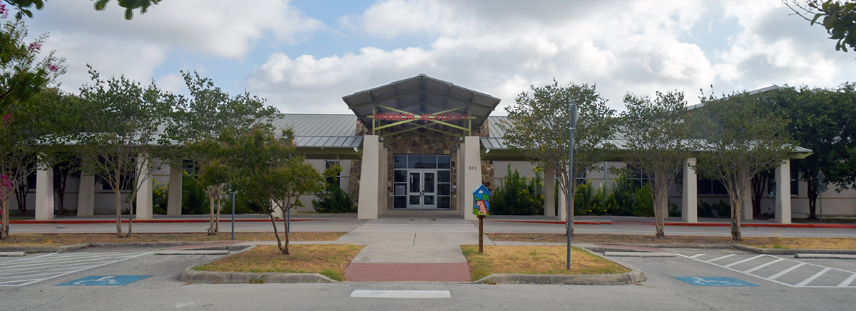 Front view of Mission academy with colorful book box and x patterned canopy above entrance.