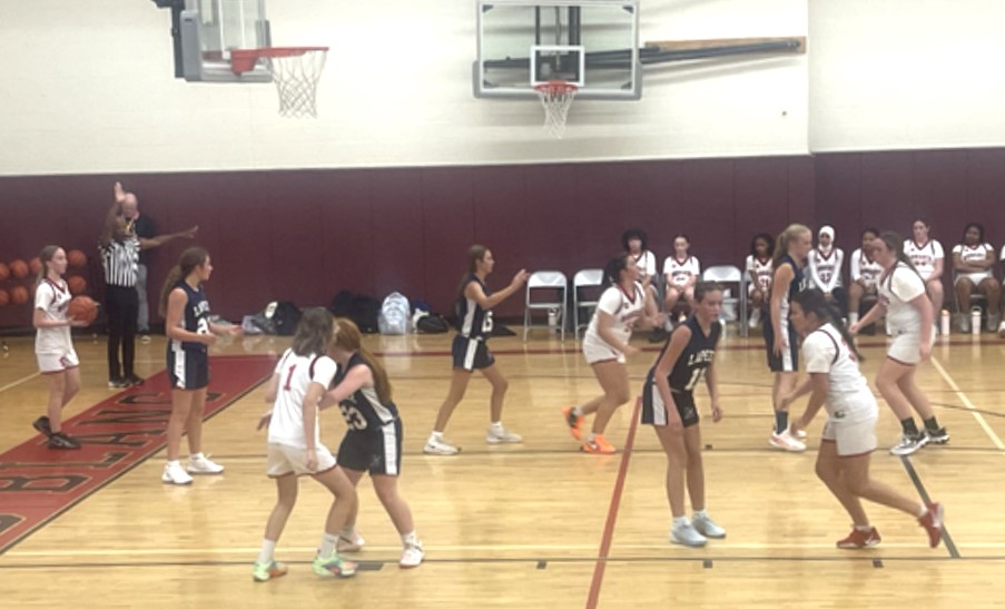 Lapeer 8th grade girls basketball players in action during a game setting up a play