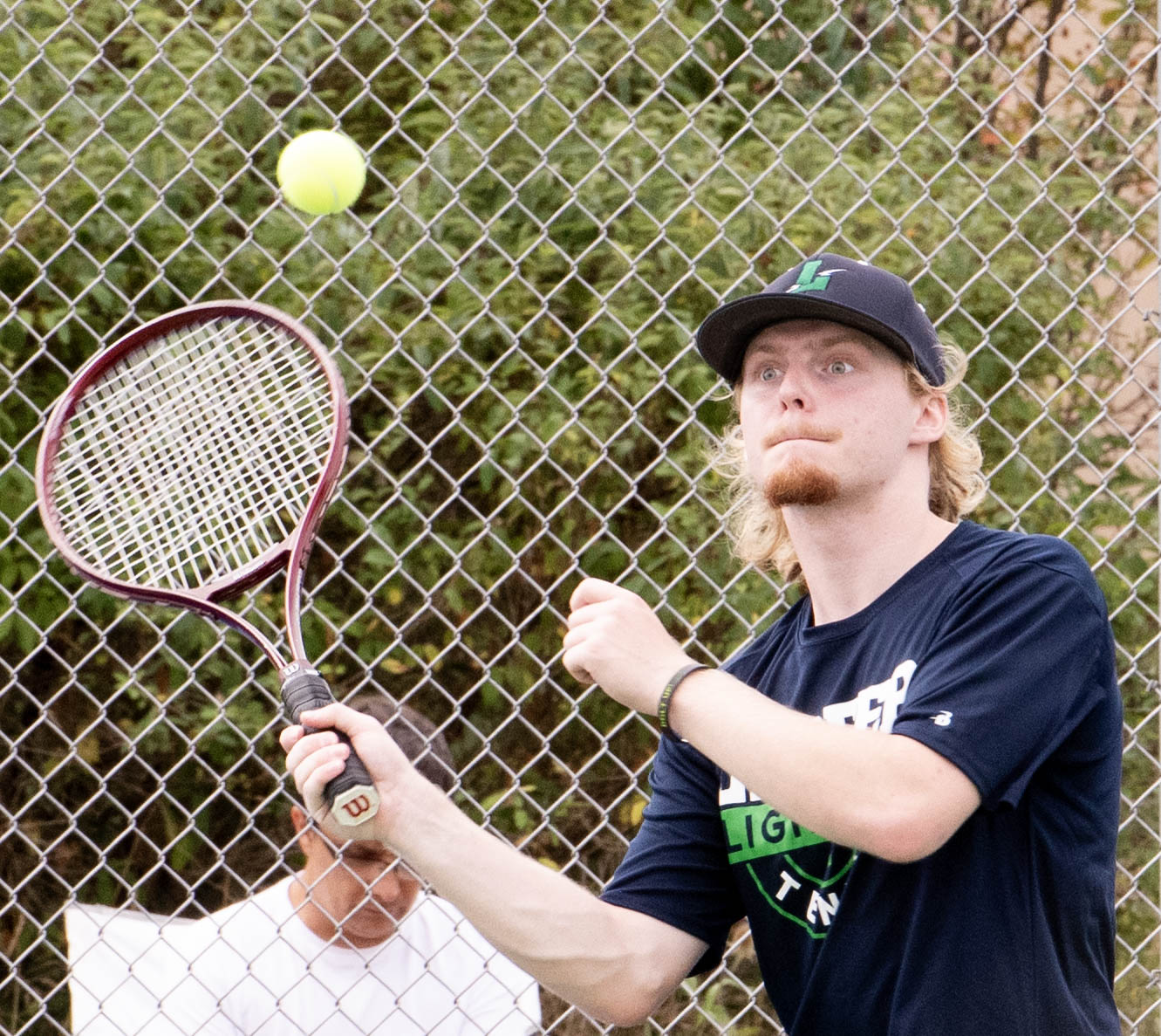 Lapeer boys tennis player concentrating on returning a serve