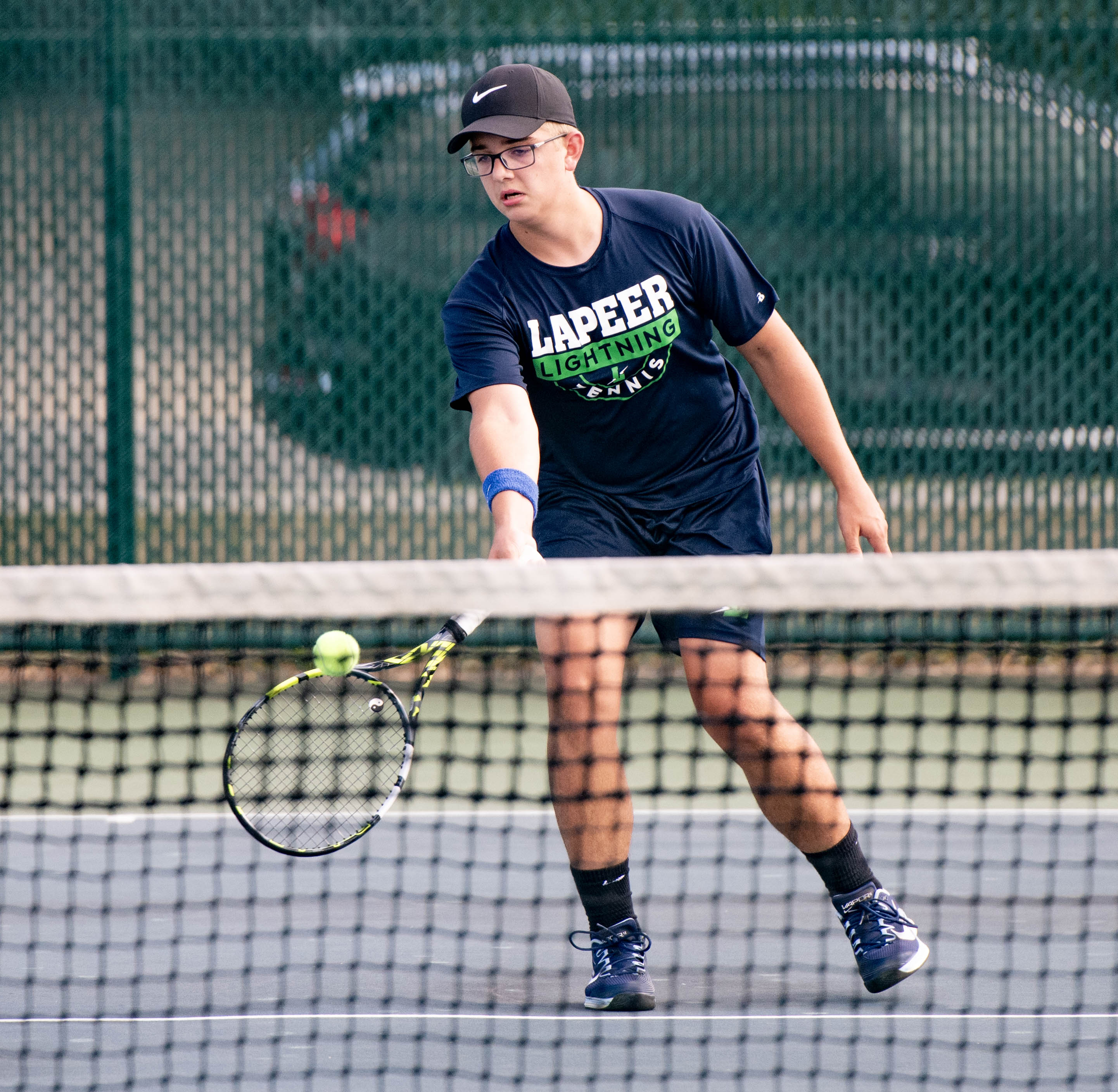 Lapeer boys tennis player at the net vs. Mount Pleasant