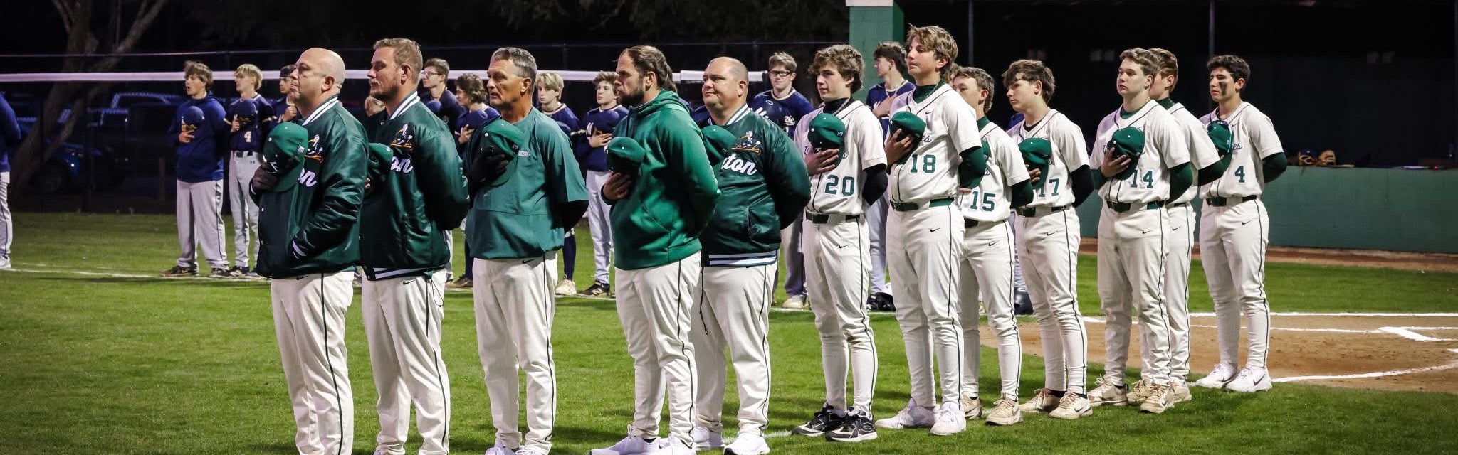 Coaches and players standing at attention for National Anthem