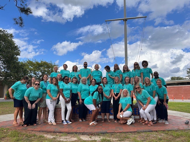A photo of the Morehead City Elementary School staff posing for a photo in front of the school.