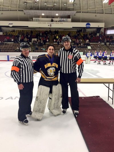 A photo of a hockey player with 2 refs