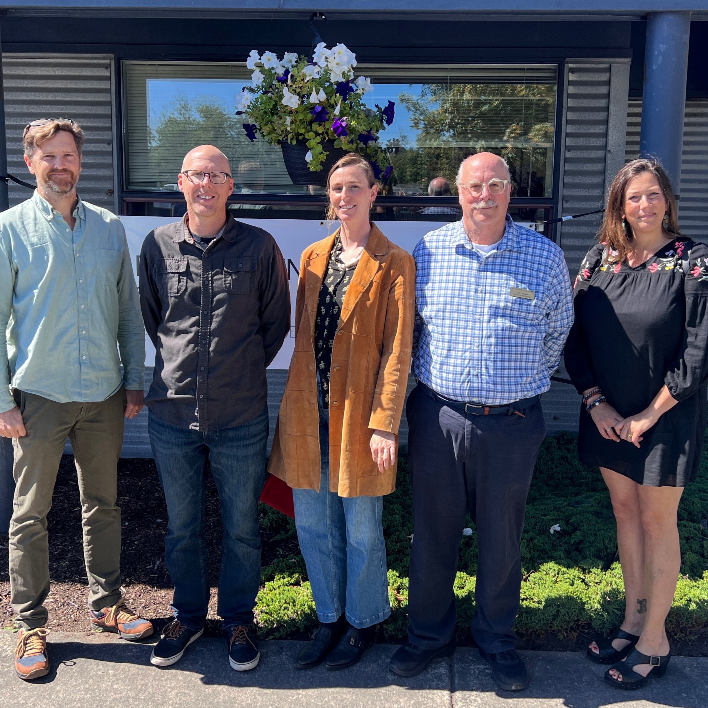 5 directors in front of the new district office building with a handing flower basket