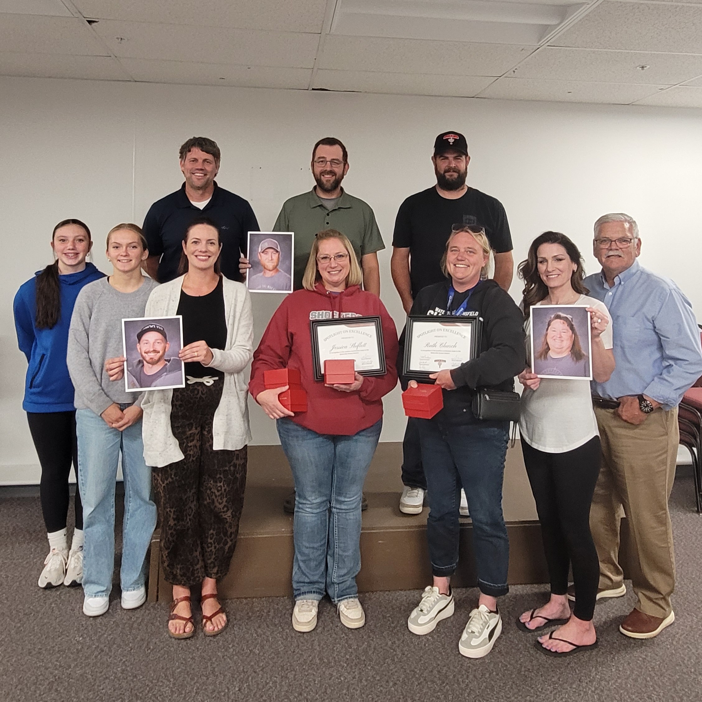 Transportation department holding pictures of their co-workers.