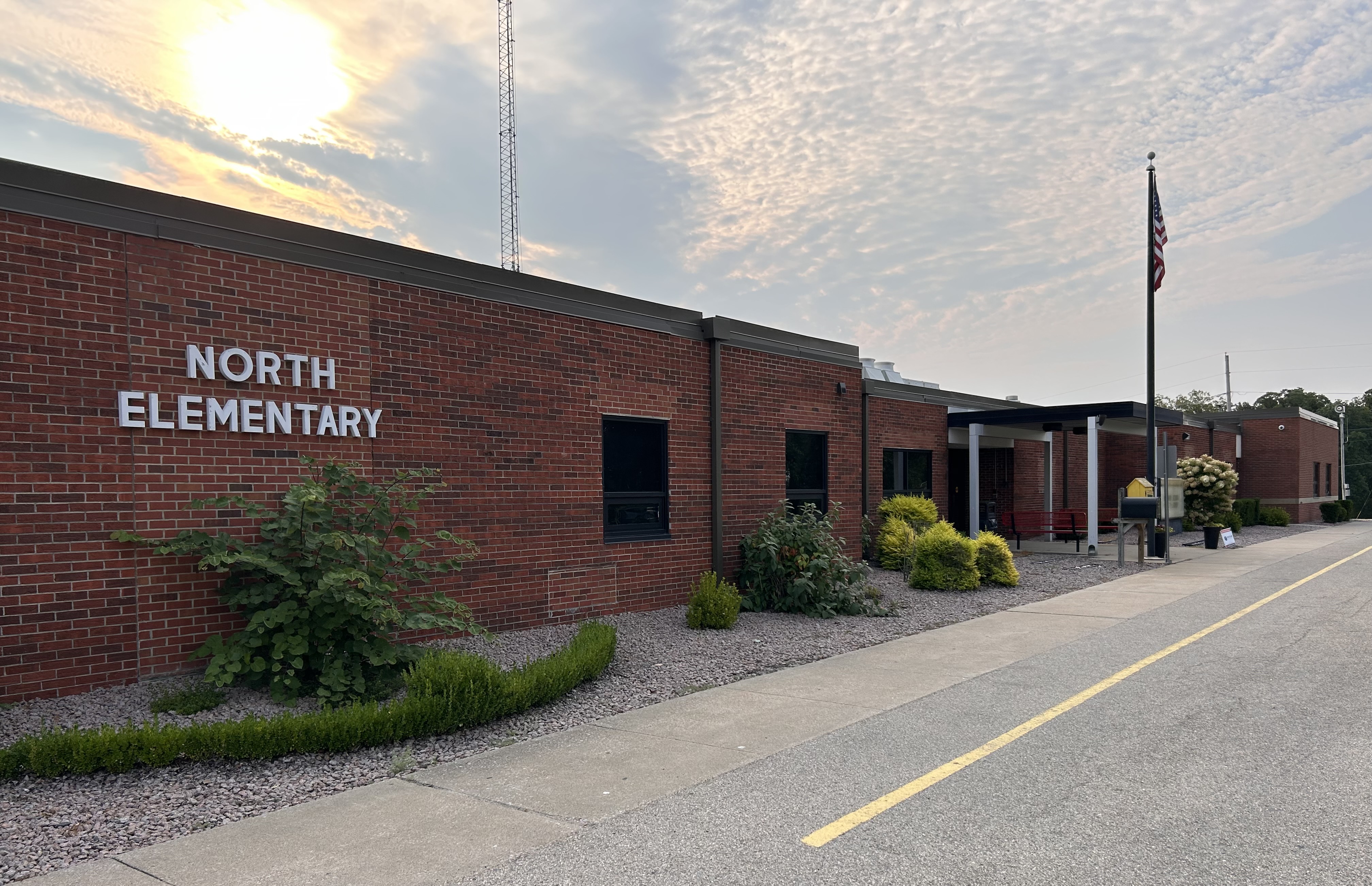 Front side of the North elementary building with the sun rising in the background.