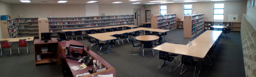 A spacious library featuring several tables and chairs arranged for reading and studying.