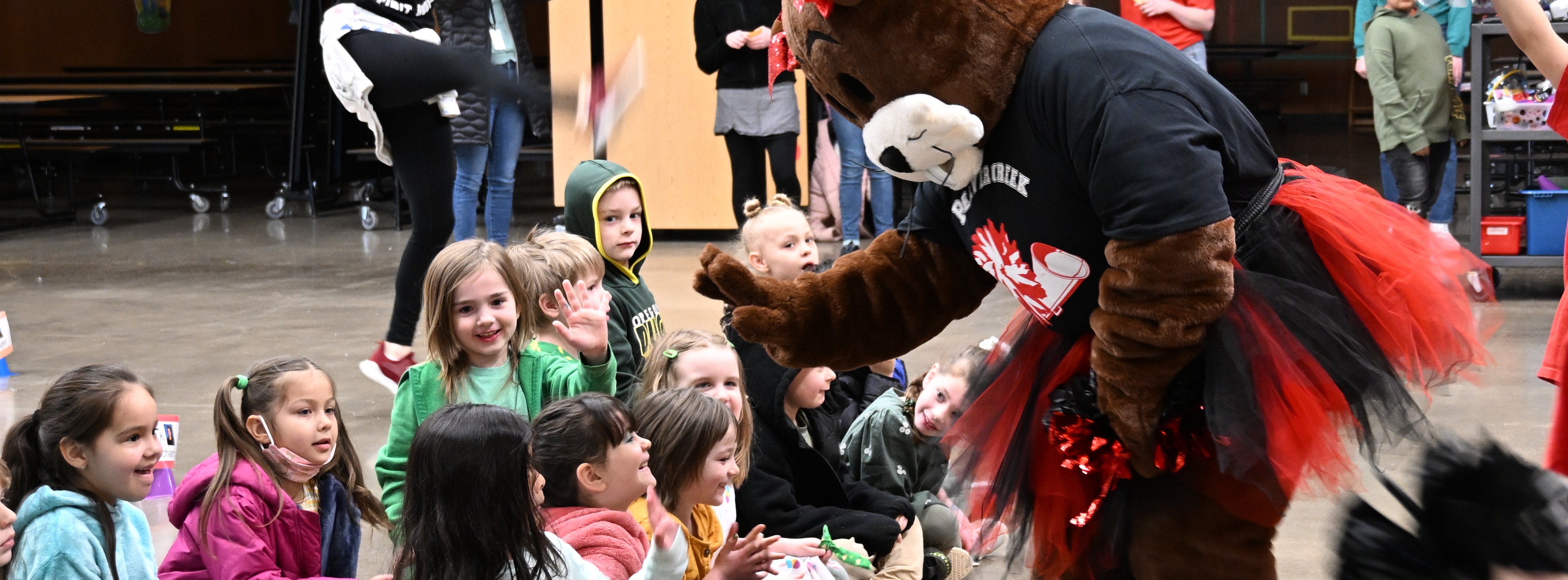 A oversized beaver mascot gives high fives at Beavercreek school