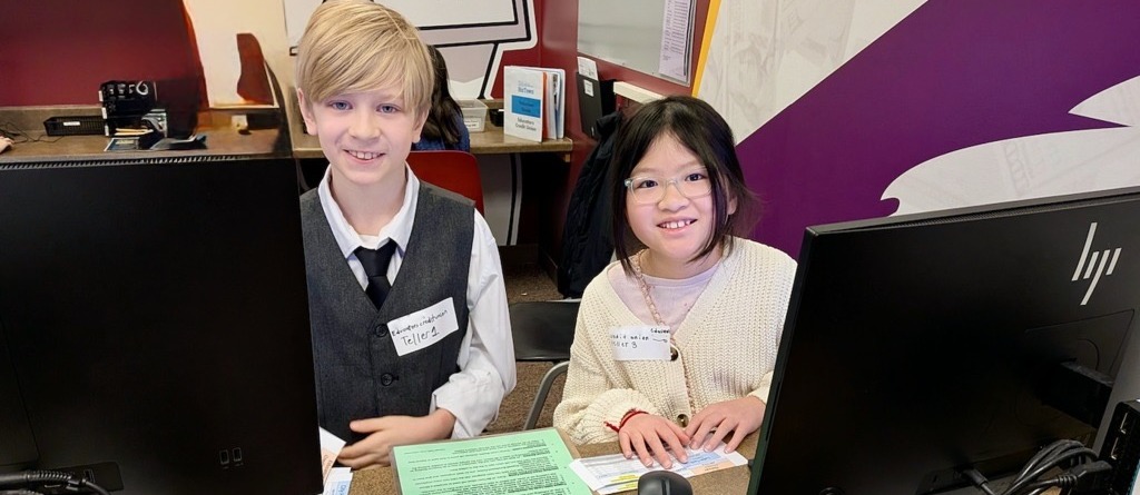 Students sitting at a desk at Biz town acting as tellers