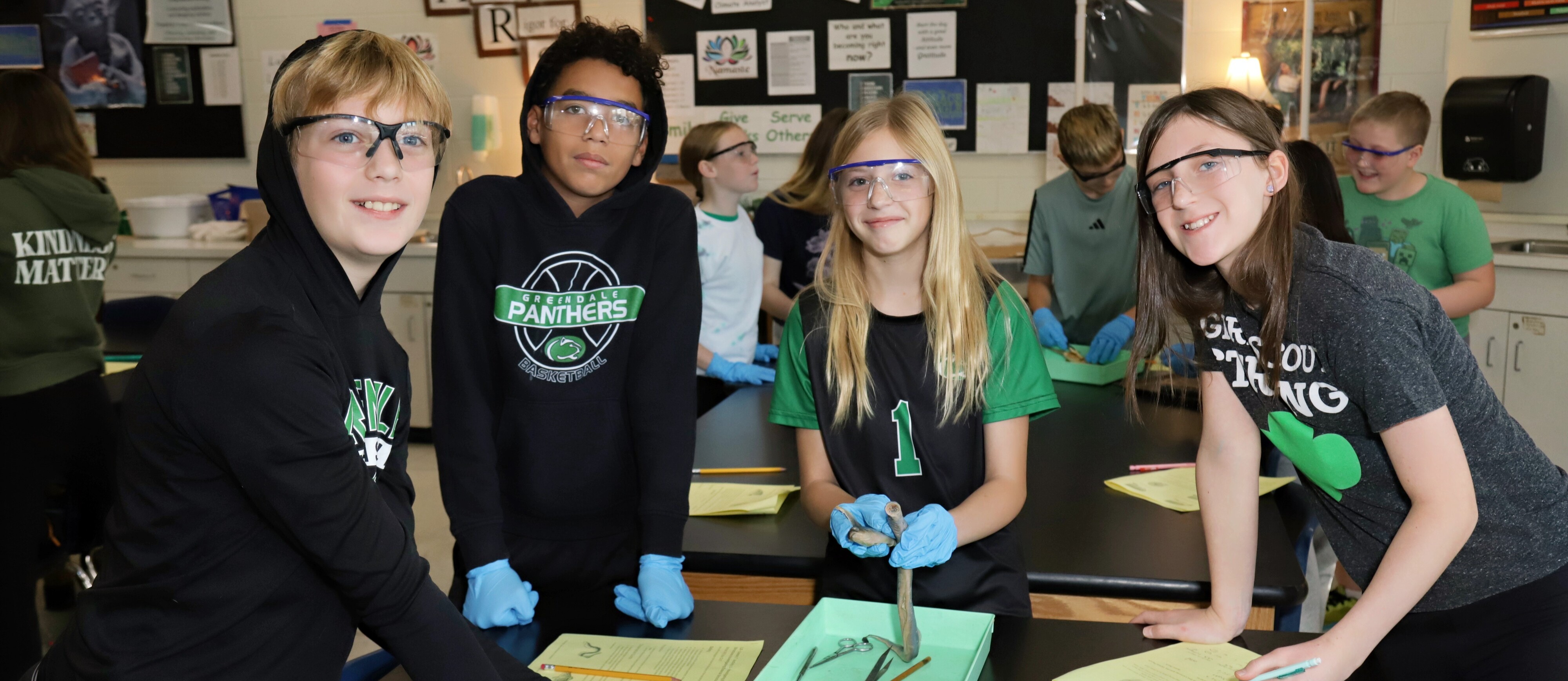 Four students dressed in Greendale colors doing a science project