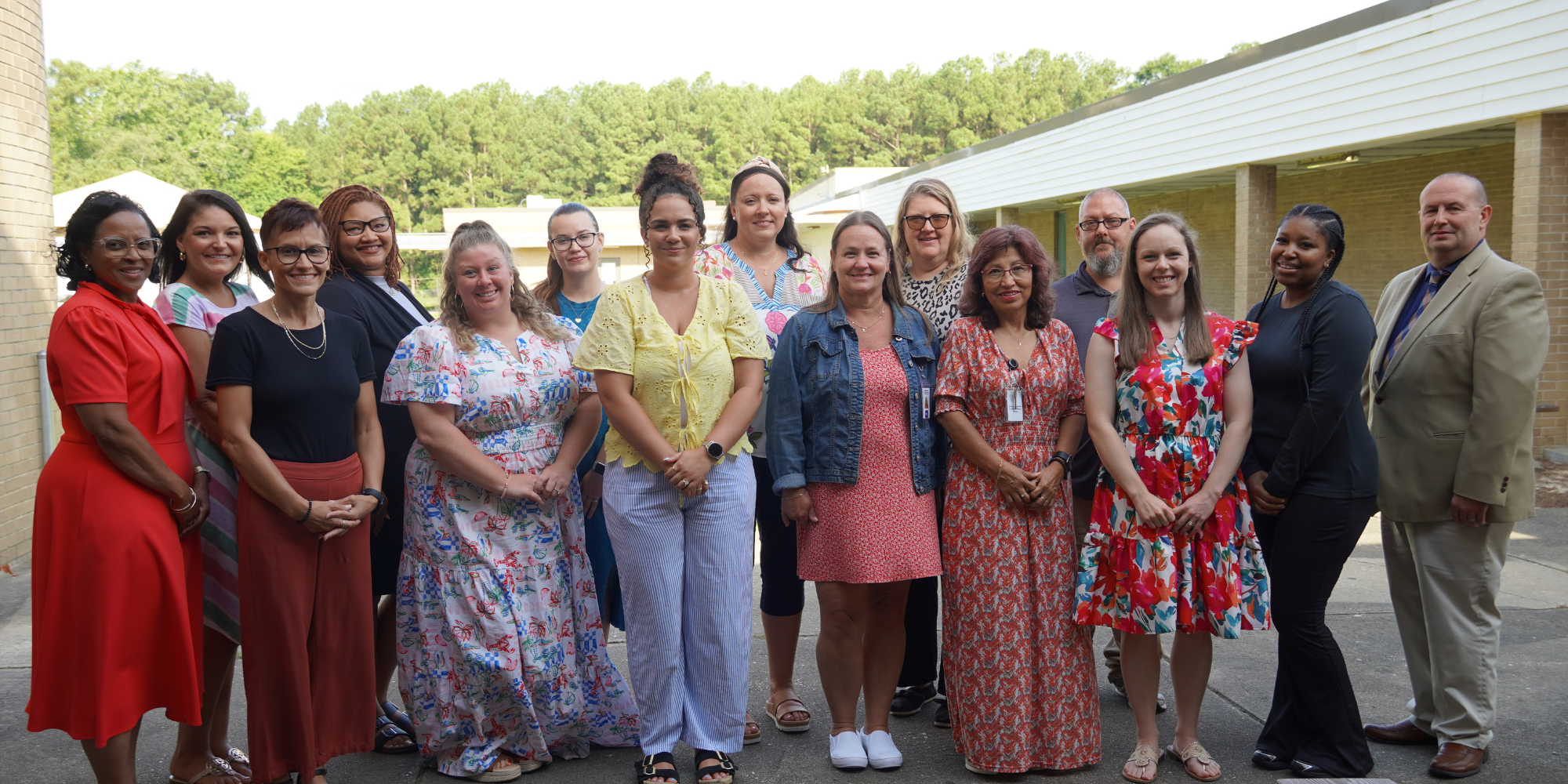 A group of employees stand smiling together outside.