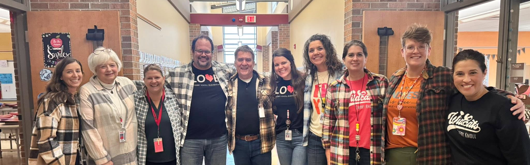 A group of ten smiling school staff members posing in a hallway under a "CK Wildcats" sign.