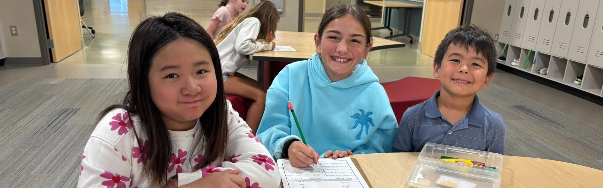 Three students smiling at the table in school