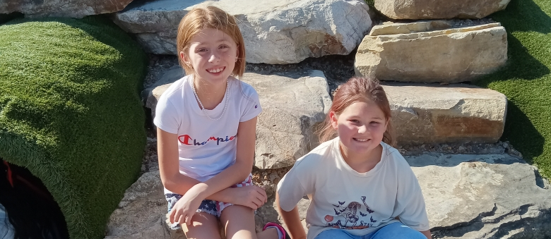 2 students sitting on rocks at a park