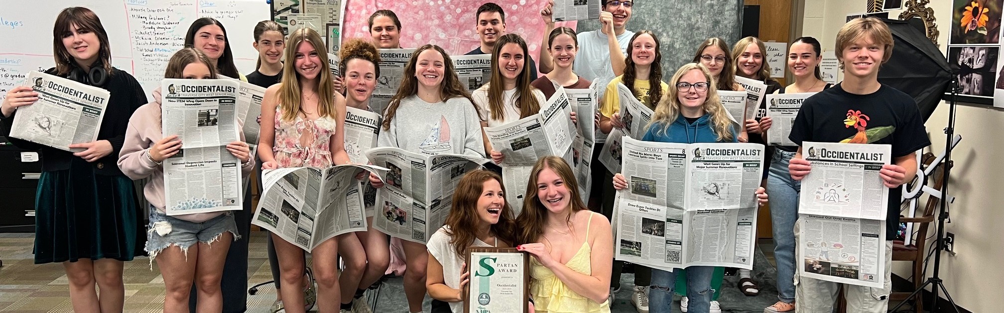 students holding their newspaper smiling