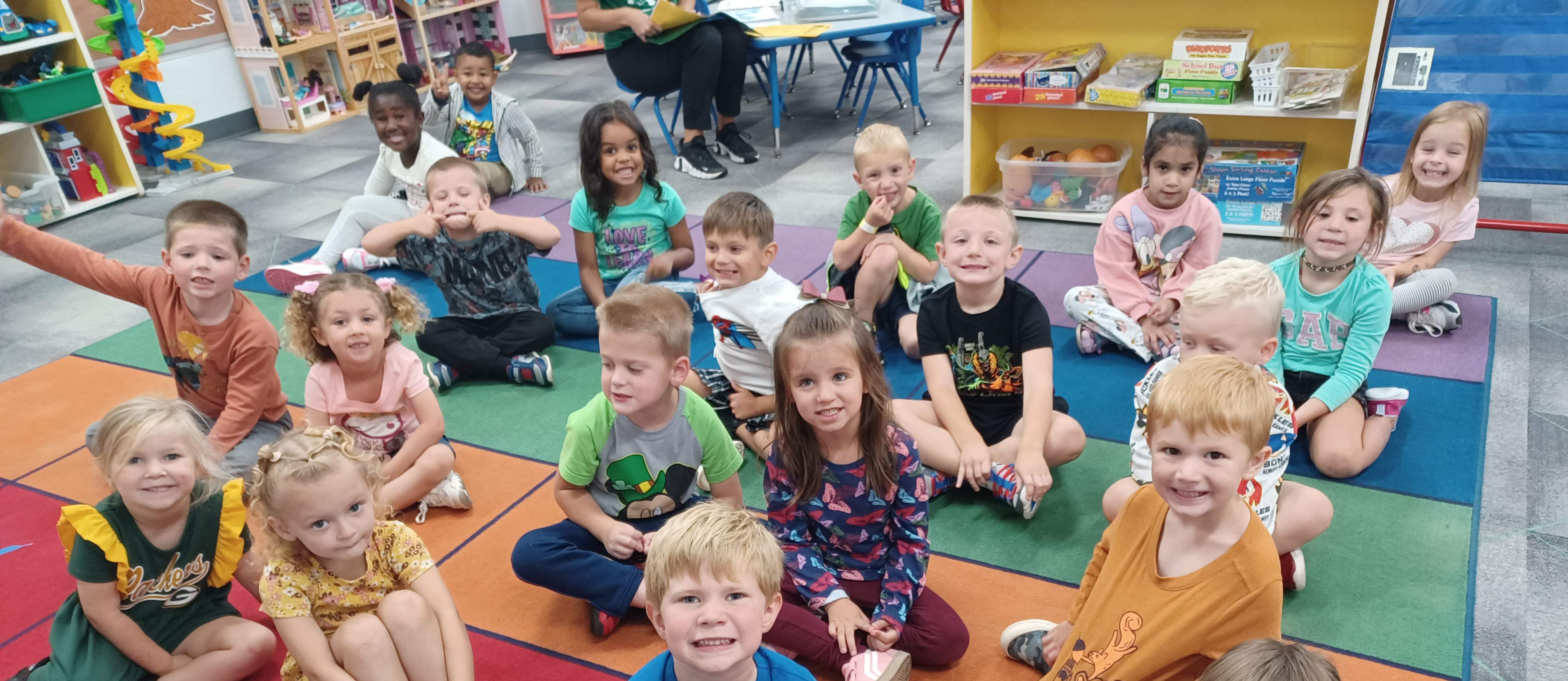Kids sitting on a rug smiling
