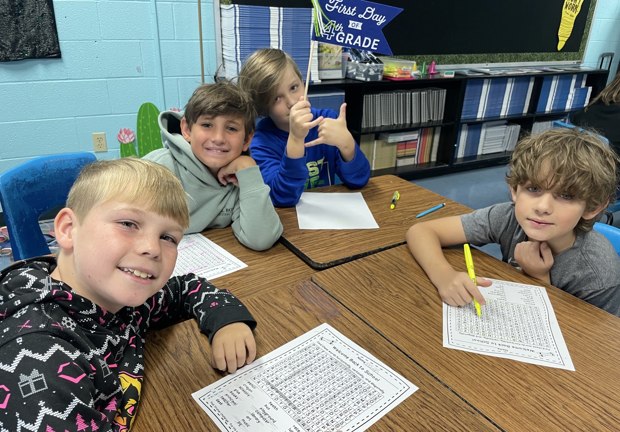 four boys smiling at a school table