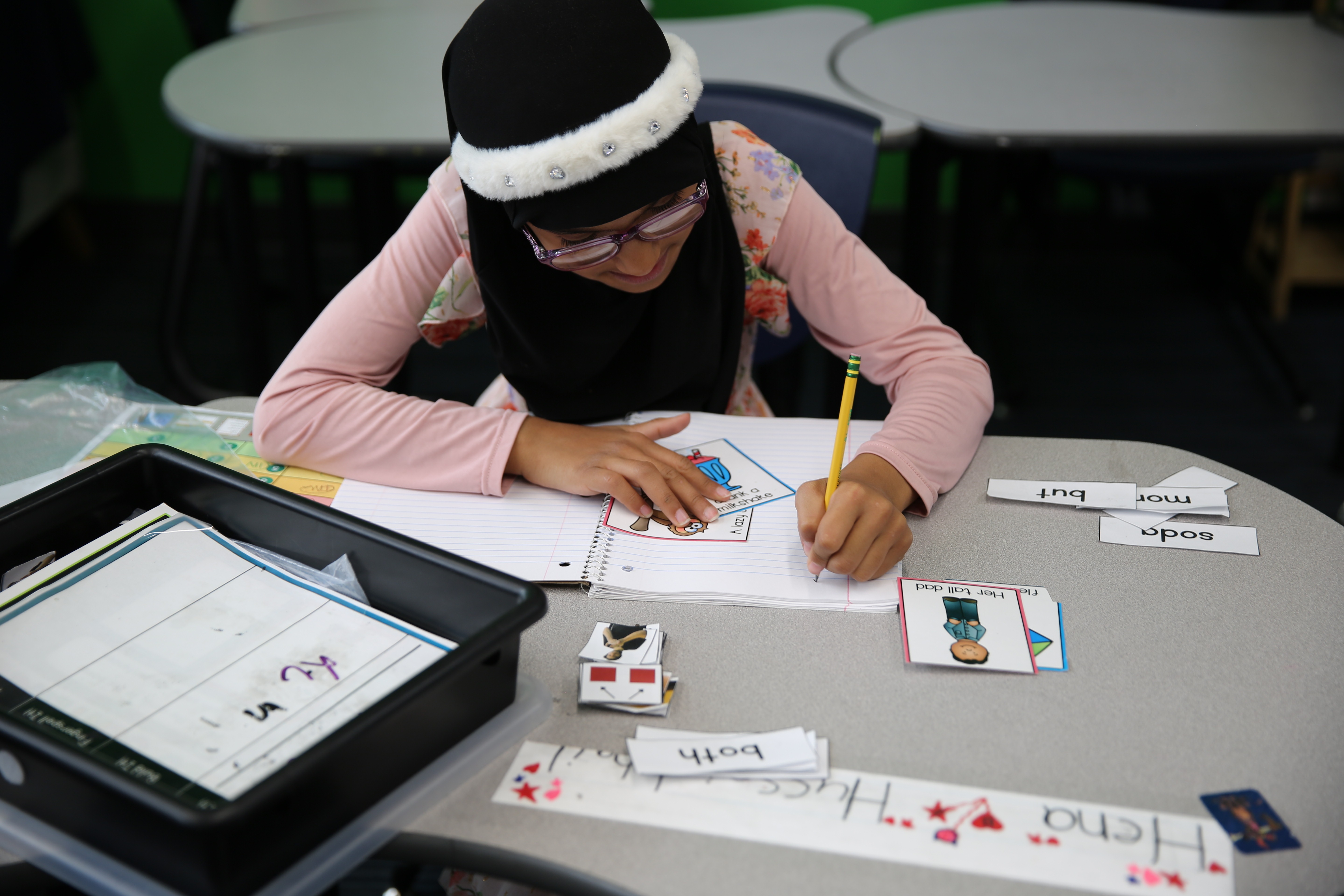 A student is writing on her notebook with flashcards on the table.