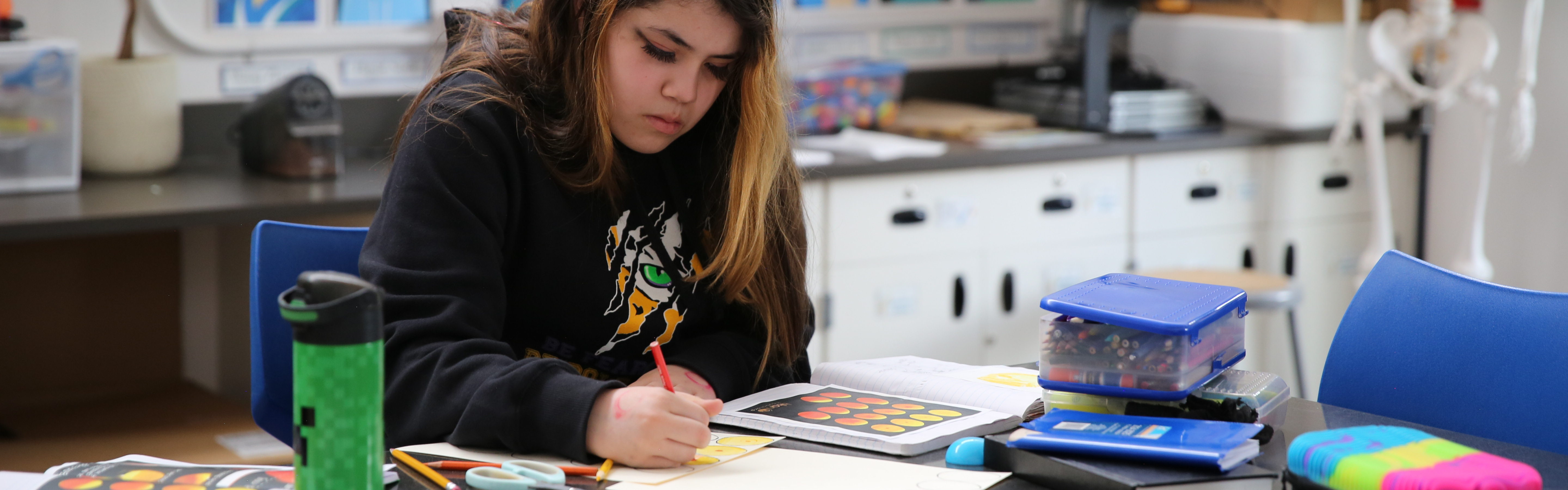 Student is writing on a paper doing school work in a science classroom