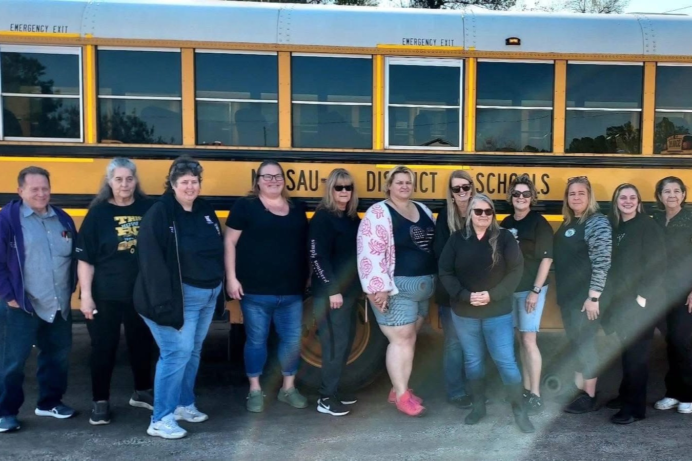 Bus drivers standing in front of a school bus