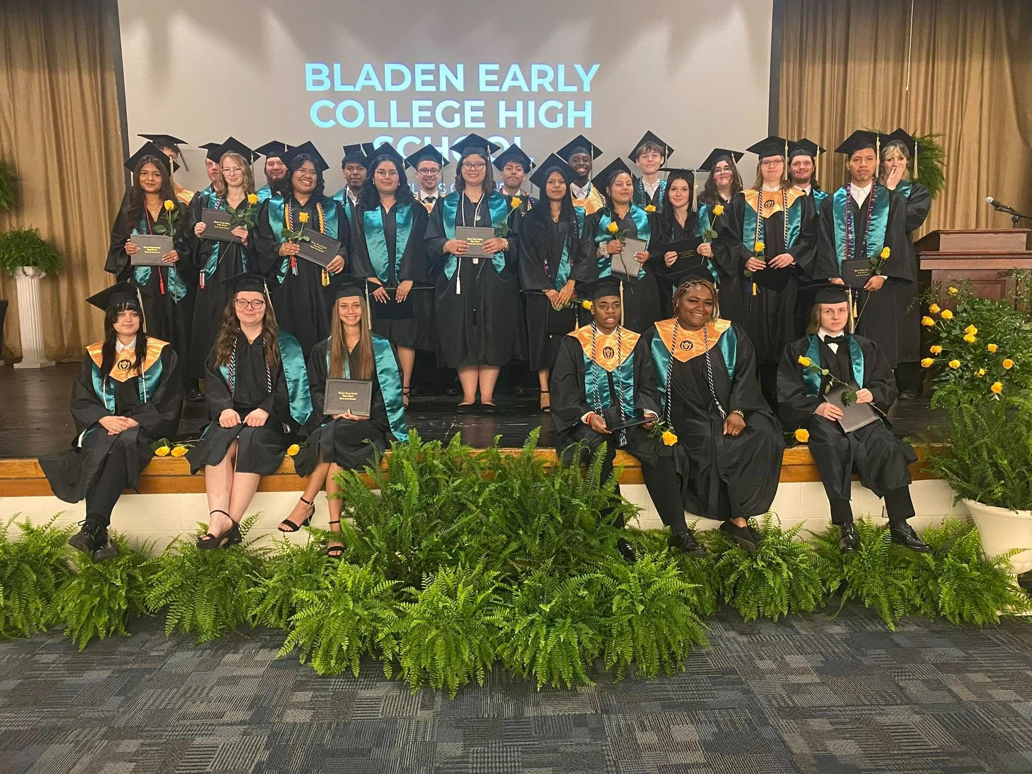 group of graduation students in black robes and teal stoles