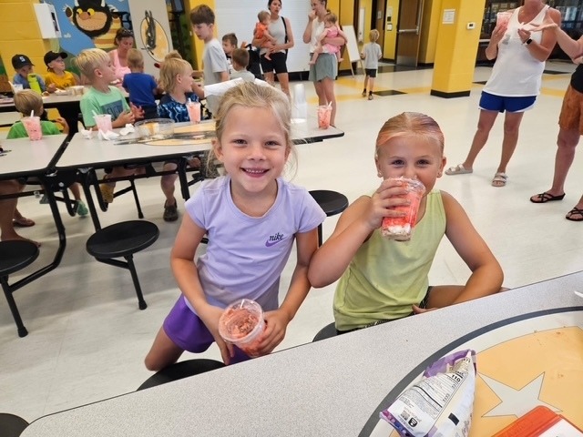 Two ACES students smiling at the camera, eating ice cream.