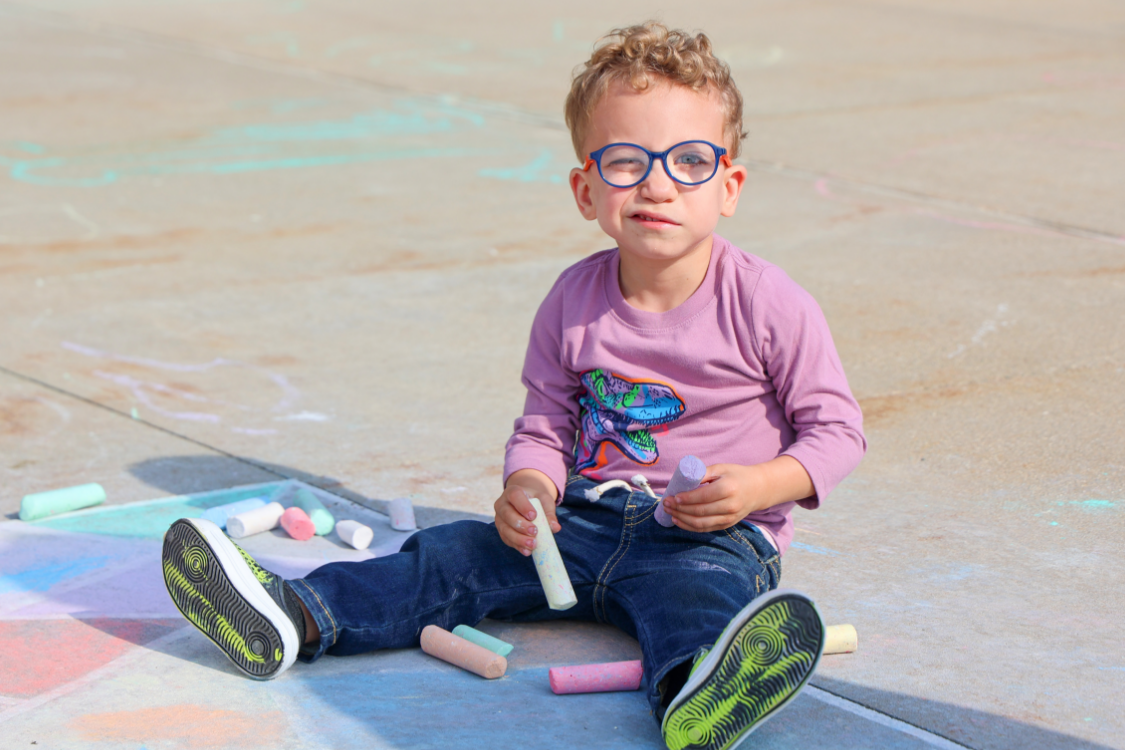 Young child at preschool playing with chalk