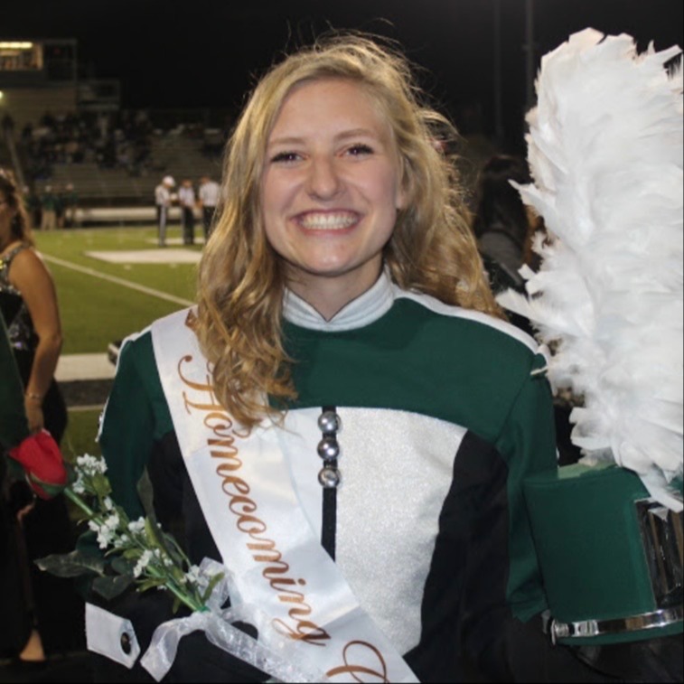 Ella dressed in her band uniform holding a rose and sporting her homecoming court sash