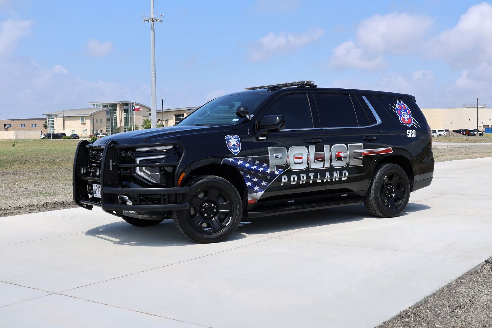 A Gregory-Portland ISD School Resource Officer (SRO) vehicle from the Portland Police Department is parked on a campus roadway, with school facilities visible in the background.
