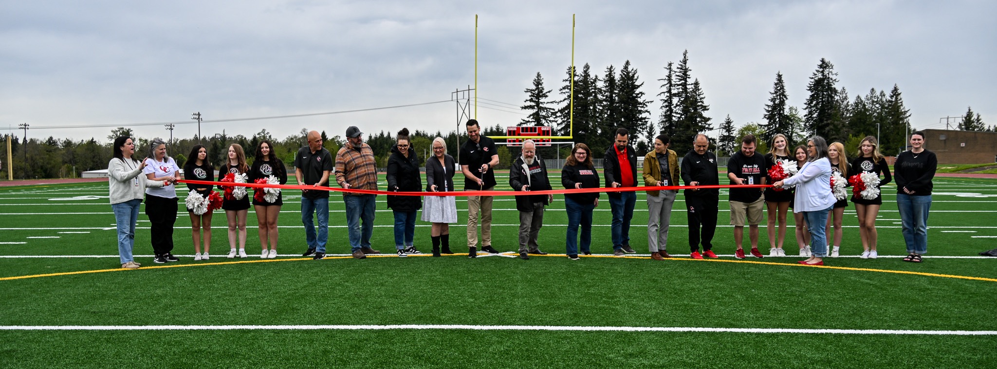 OCHS students, staff, community members gather behind a red ribbon for a ribbon cutting ceremony