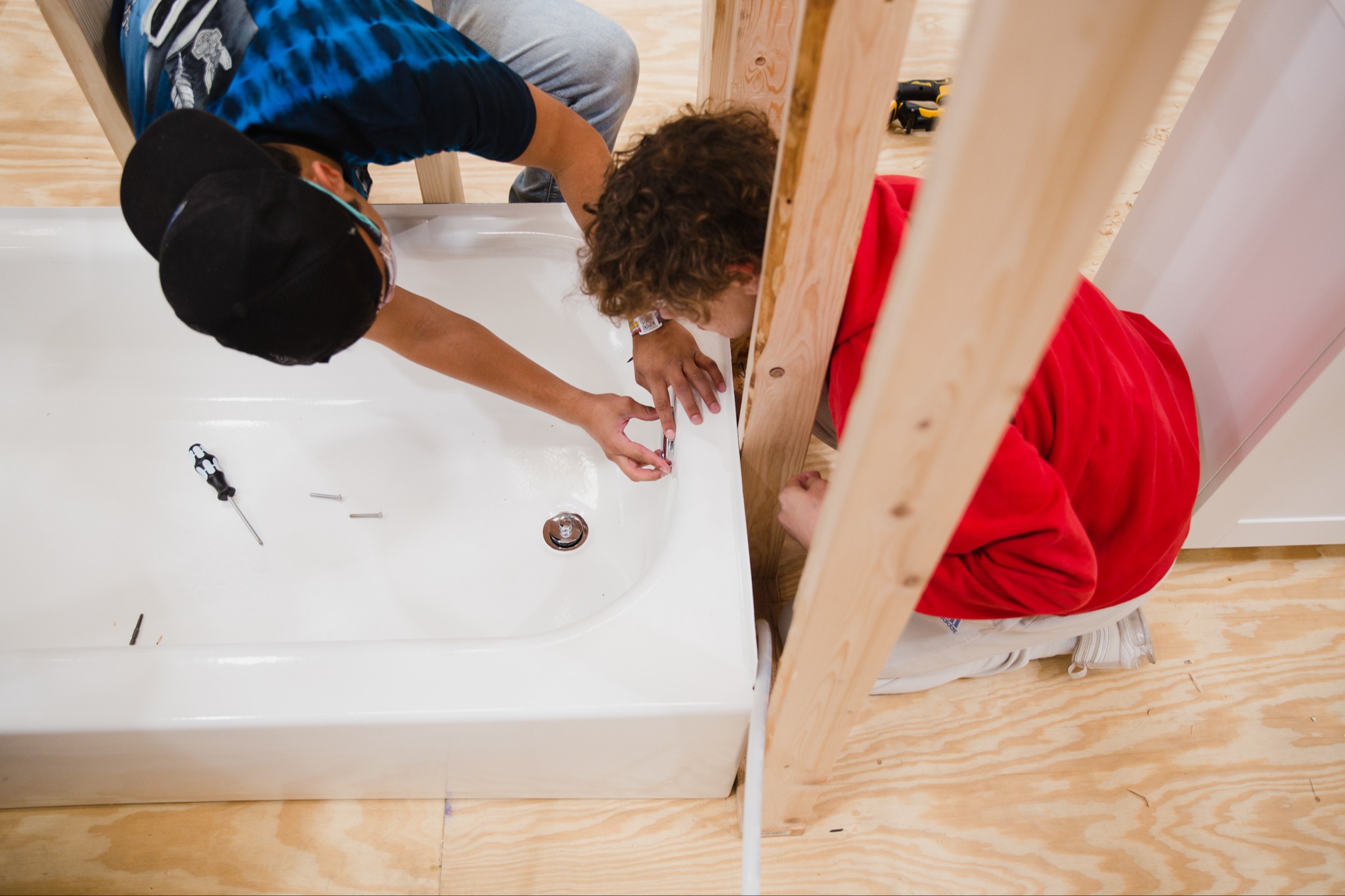 Two plumbing students working on the plumbing for a bath tub