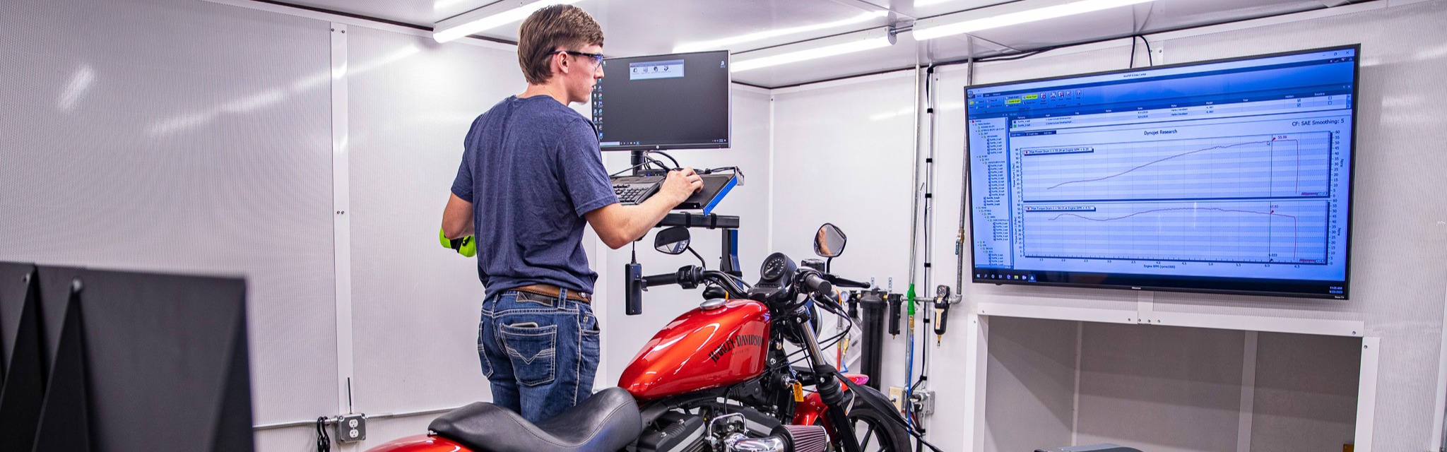 Central Tech student in the power sports class works on a computer with a motorcycle next to him.