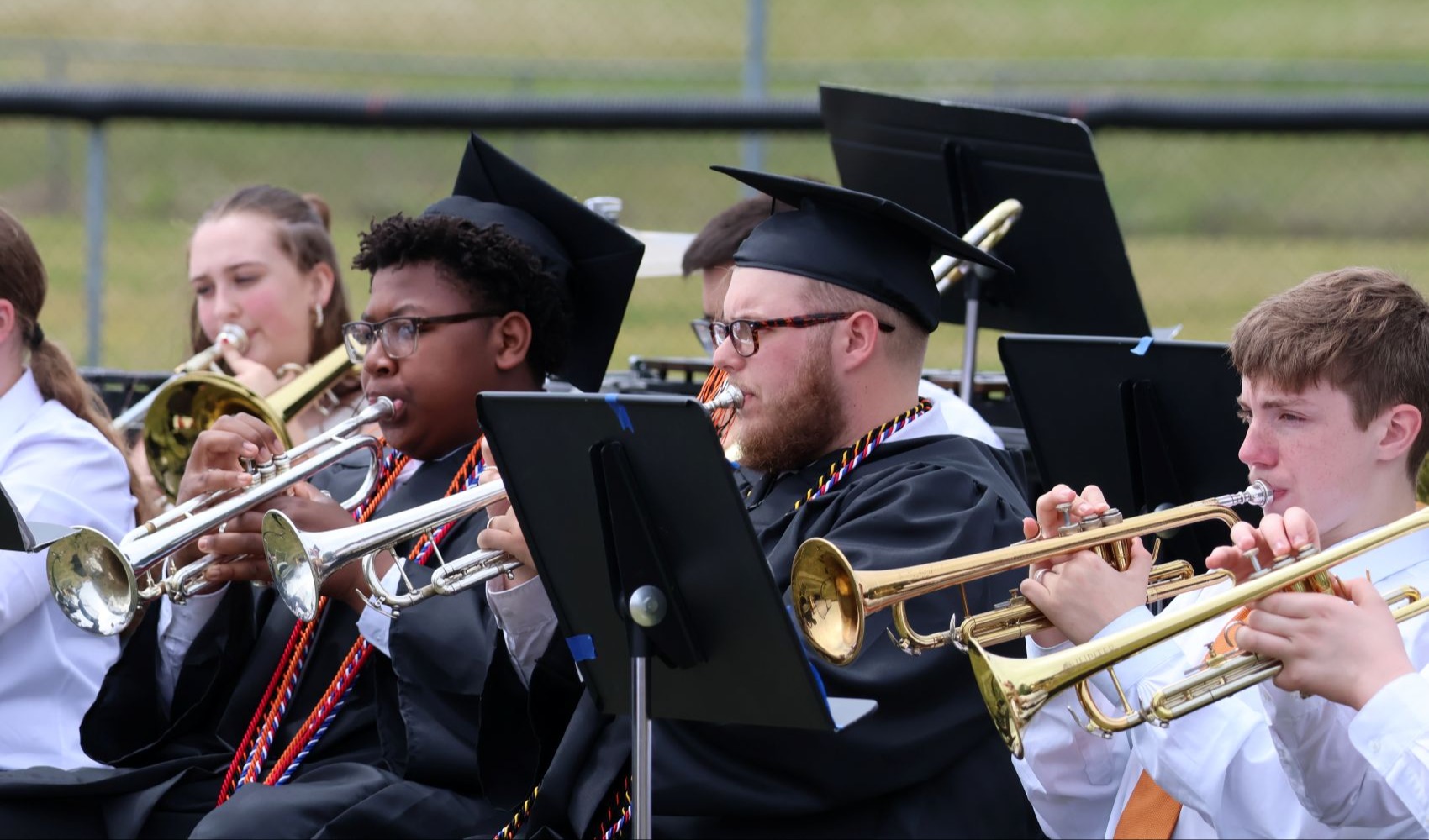 Two graduates are playing with the band at graduation.