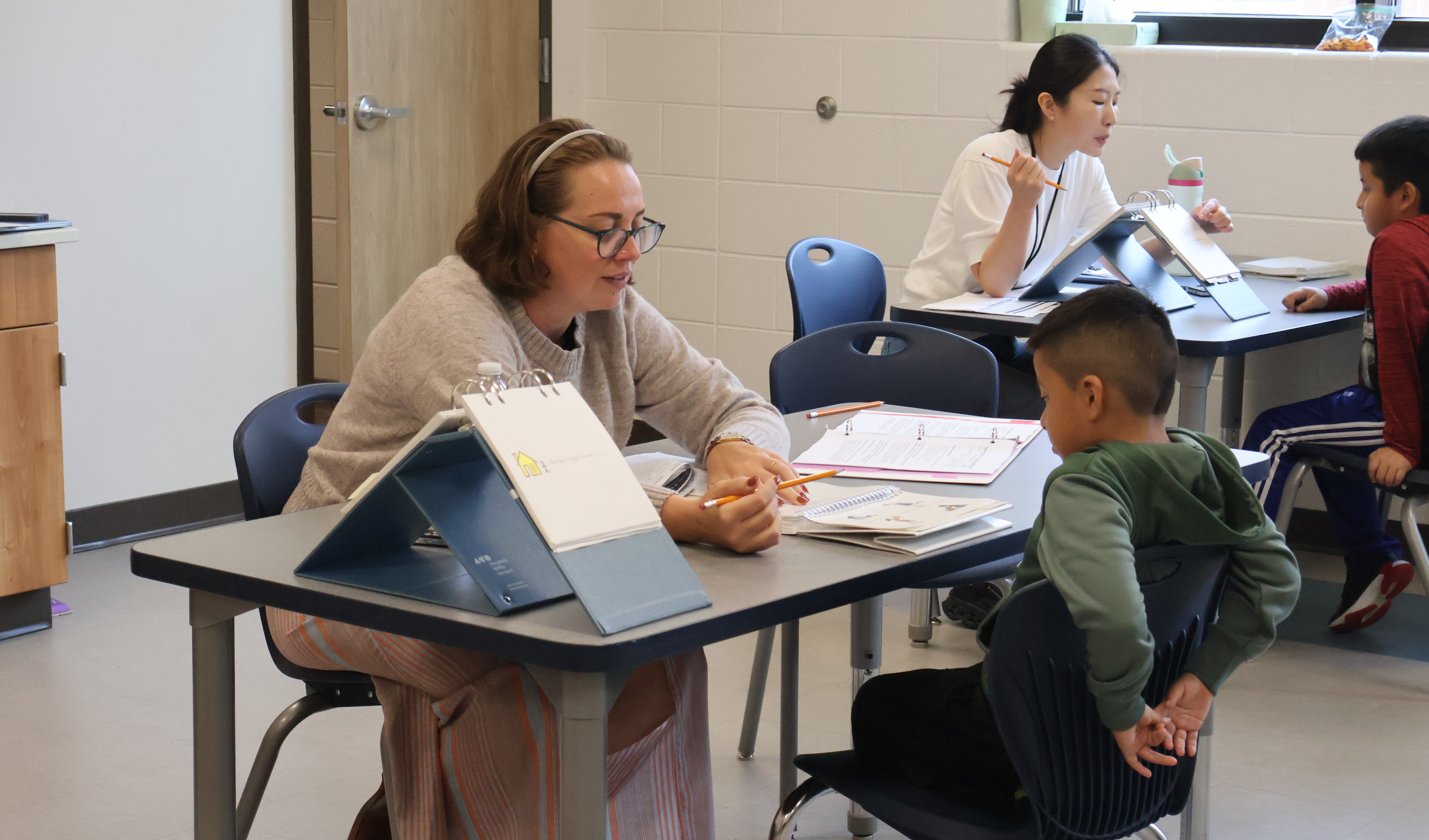 Two MTSU Doctoral students are sitting with elementary students while they are testing them. 
