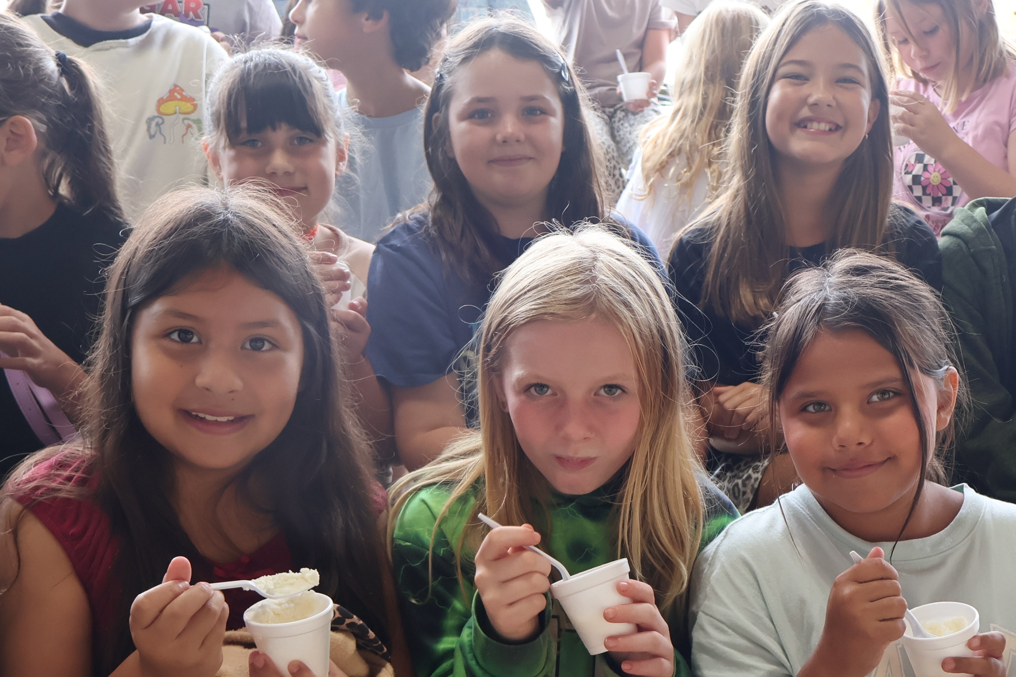 There are six girls all posed for a picture eating ice cream at the Mule Day festival.