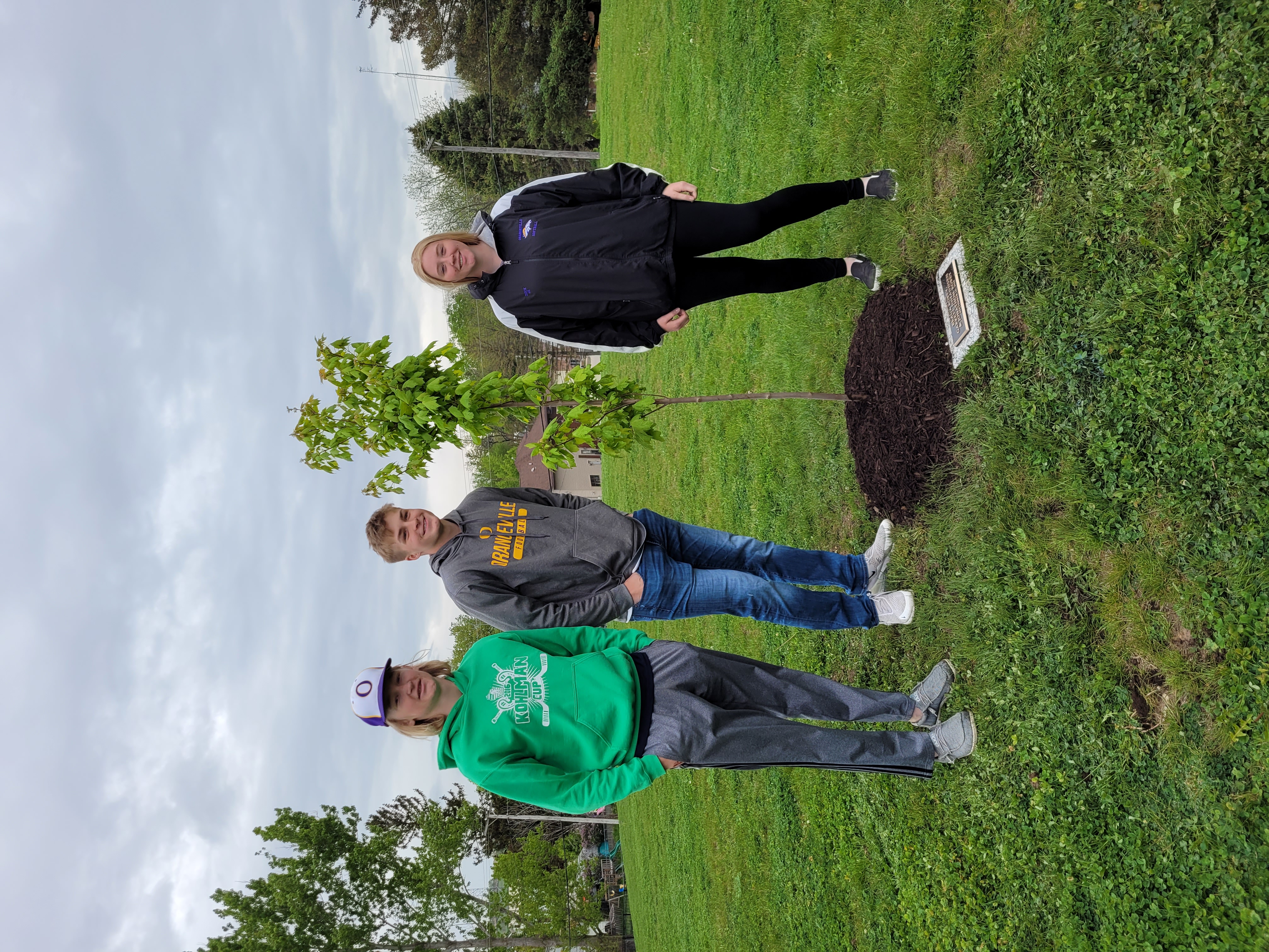 3 students next to newly planted tree