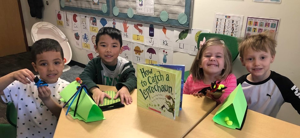 students smiling at a table with books