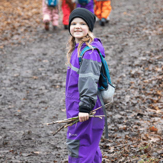 photo of Charlie walking in the woods, carrying some sticks