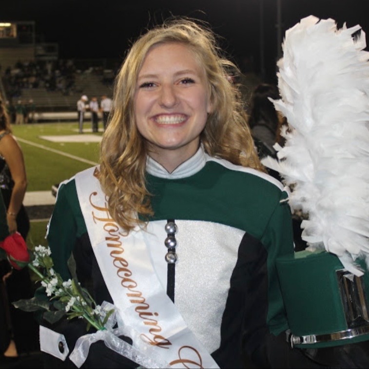 Ella dressed in her band uniform holding a rose and sporting her homecoming court sash