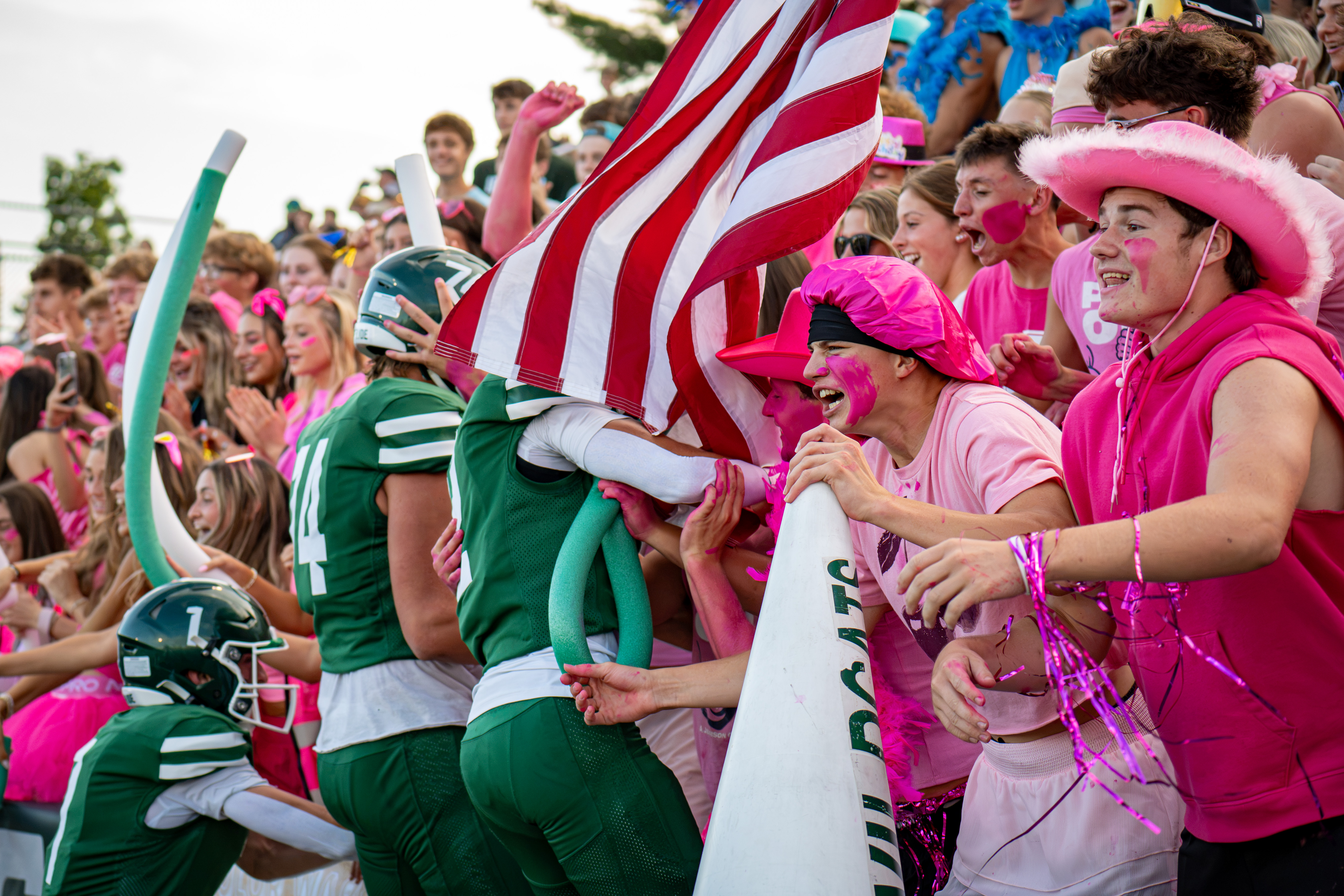 Students cheering as football team jumps in crowd