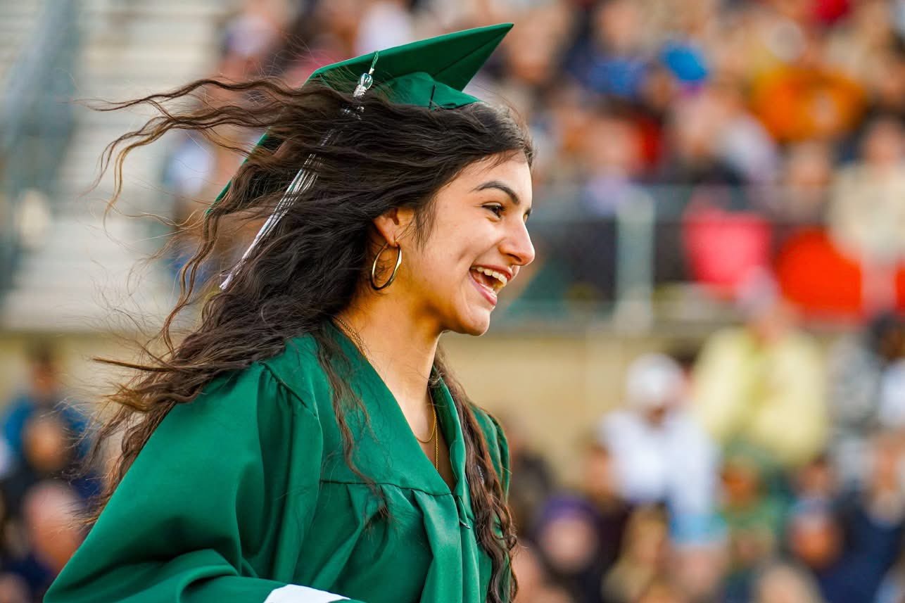 A graduate crosses the stage receiving her diploma.